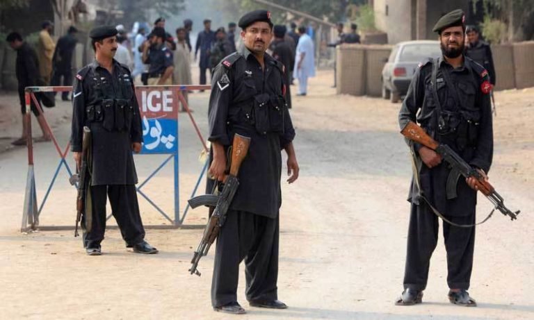 Policemen stand guard at a checkpoint after it was attacked by a hand grenade in the outskirts of Peshawar